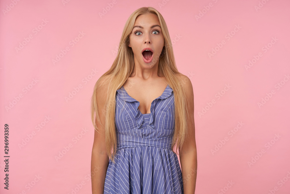 Studio shot of amazed young blonde female with casual hairstyle posing over pink background with hands down, looking surprisedly at with wide mouth opened, Human emotions concept Studio shot of amazed young blonde female with casual hairstyle posing over pink background with hands down, looking surprisedly at with wide mouth opened, Human emotions concept