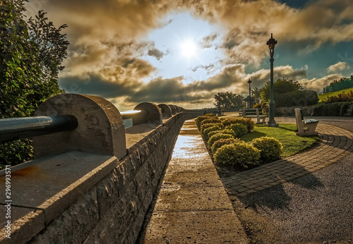 Quebec City, PQ, Canada - - September 3, 2014: La Terrasse Saint-Denis on a moody, damp autumn morning with the sun shining through clouds looking east, with wall, puddles, benches and lamp posts