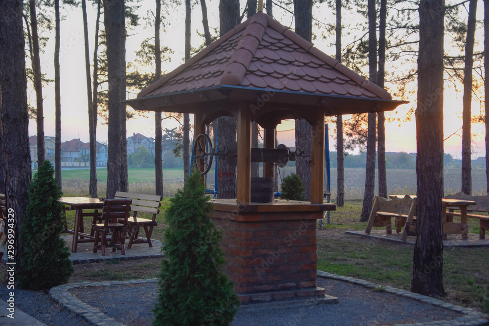 the well in the forest with the sunset in the back of the picture the well in the forest with the sunset in the back of the picture