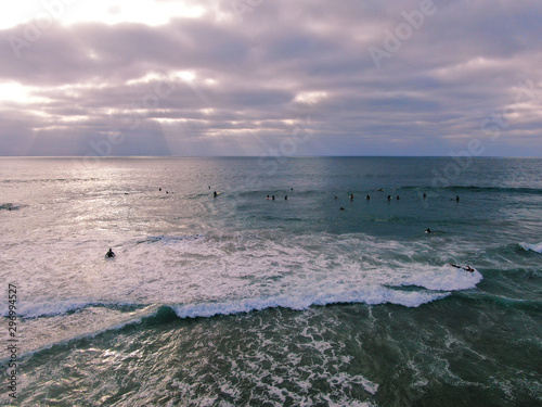 Aerial view of surfers waiting, paddling and enjoying waves before sunset time. Del Mar Beach, California, USA