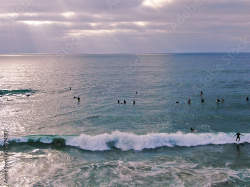 Aerial view of surfers waiting, paddling and enjoying waves before sunset time. Del Mar Beach, California, USA