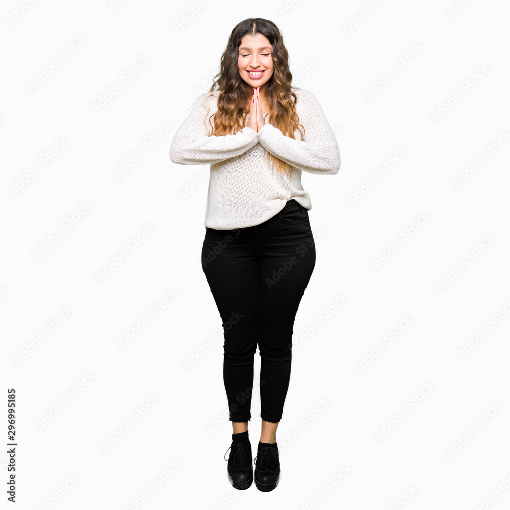 Fototapeta premium Young beautiful woman wearing white sweater praying with hands together asking for forgiveness smiling confident.