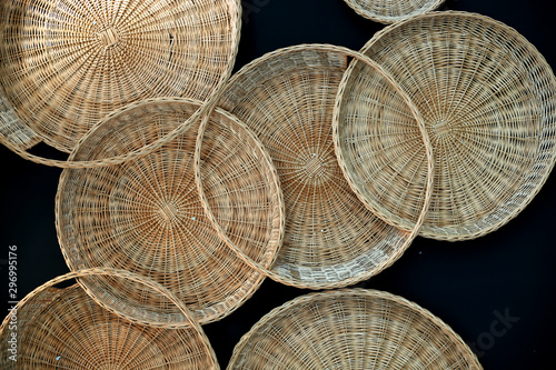 Rattan sift and basket hanging on the black wall. Decorative element in the home interior.