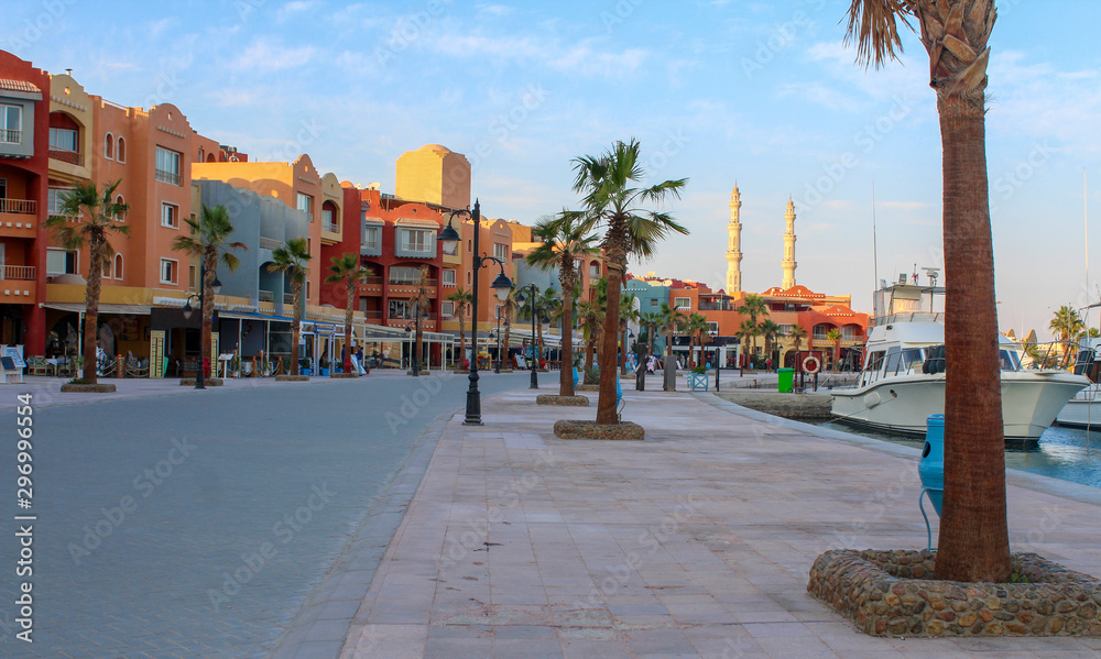 Obraz premium Hurghada, Egypt. Promenade and harbor in the Red Sea. View of embankment with houses, moored yachts and mosque.