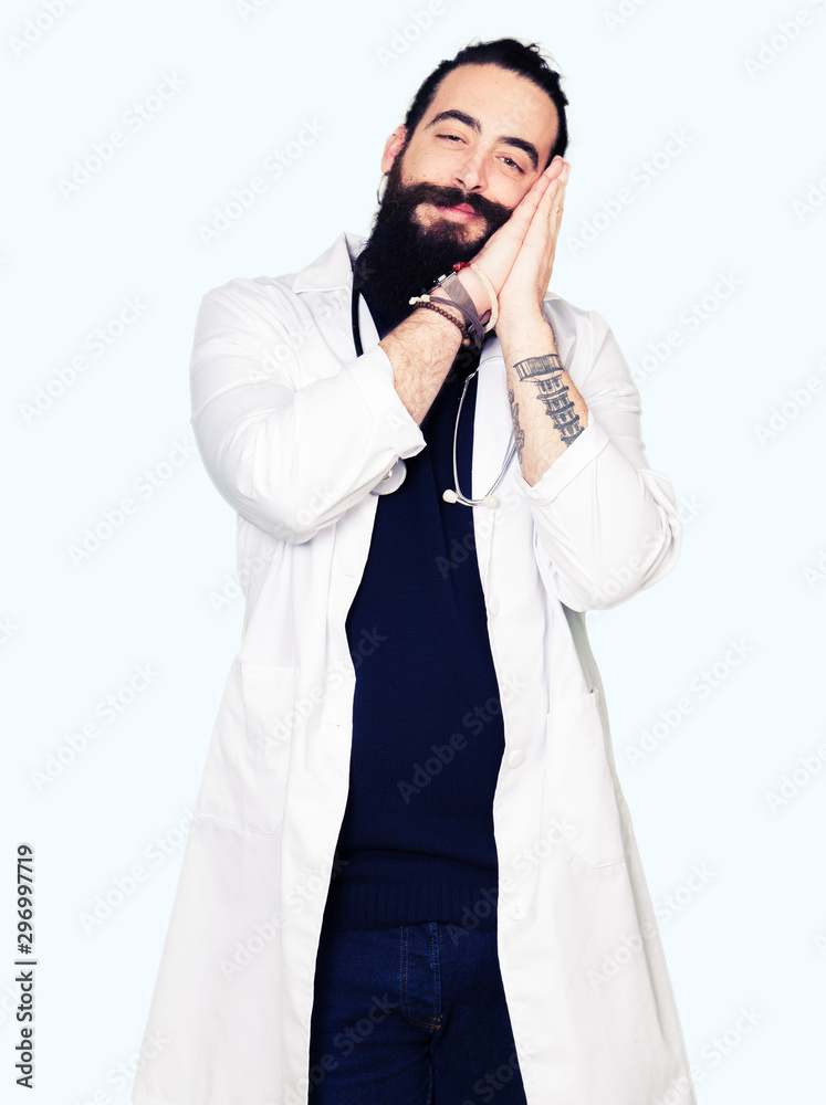 Doctor with long hair wearing medical coat and stethoscope sleeping tired dreaming and posing with hands together while smiling with closed eyes. Doctor with long hair wearing medical coat and stethoscope sleeping tired dreaming and posing with hands together while smiling with closed eyes.