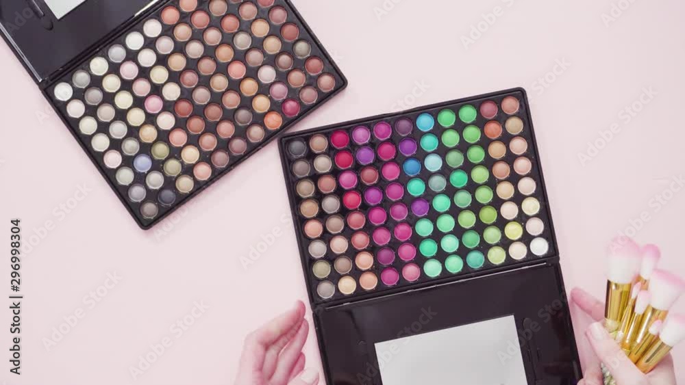 Flat lay. New eyeshadow palette with makeup brushes on a pink background. Flat lay. New eyeshadow palette with makeup brushes on a pink background.