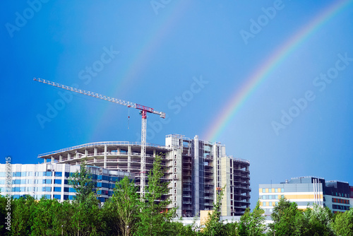 Rainbow over the building under construction and construction crane .
