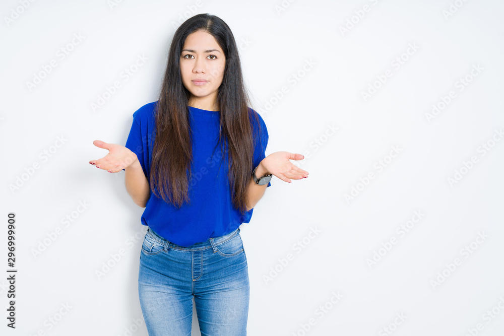 Beautiful brunette woman over isolated background clueless and confused expression with arms and hands raised. Doubt concept.