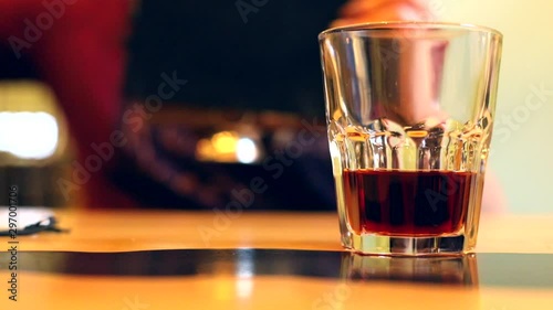 Closeup view of glass with brown dark rum alcohol drink on the table with female person on background. Cafe bar restaurant service. Woman drinking beverage. Business weekend friends. Alcohol addiction