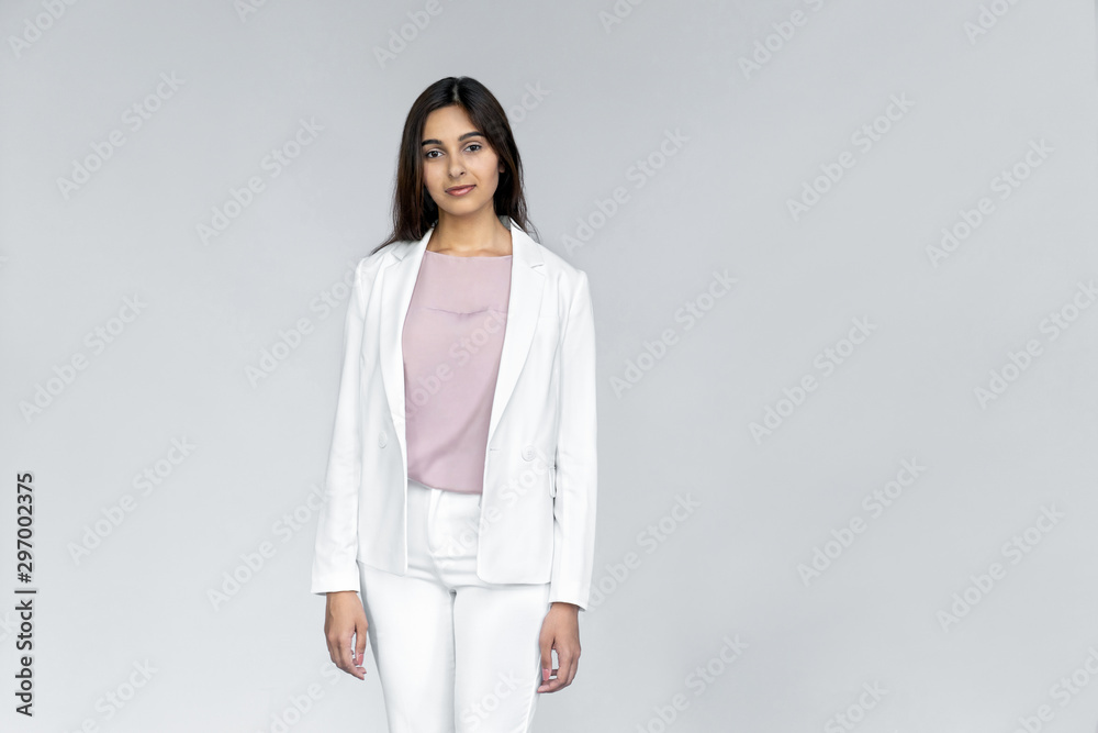 Photo of successful young adult indian office businesswoman professional corporate teacher saleswoman in white formal wear suit standing isolated on grey background with looking at camera, portrait Photo of successful young adult indian office businesswoman professional corporate teacher saleswoman in white formal wear suit standing isolated on grey background with looking at camera, portrait
