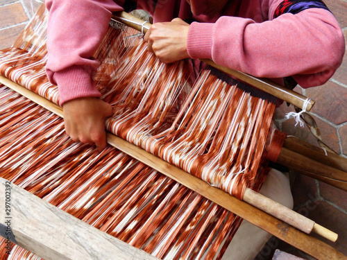 Close up man's arms wprking on traditional weaving technique Ikat for making scarfs or Macana or other fabric by hand with cotton threads, design are traditional for Gualaceo, Azuay province, Ecuador photo