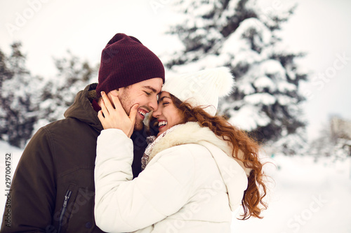 Young couple on the snow in winter in the park photo