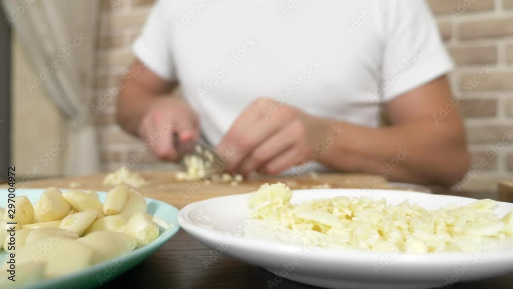 male hands cut garlic on a wooden board. close-up male hands cut garlic on a wooden board. close-up