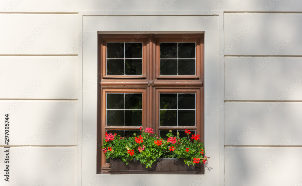 window on white house wall with red flowers 