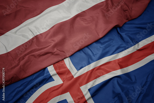 waving colorful flag of iceland and national flag of latvia.
