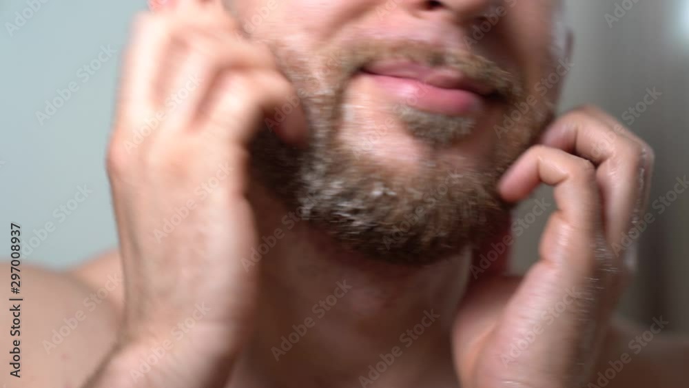 Close-up shot of man's morning facial procedures in front of the mirror. Skincare and shaving hygiene at home. Man pouring shaving shampoo and making foam. Brutal man preparing his beard for shaving Close-up shot of man's morning facial procedures in front of the mirror. Skincare and shaving hygiene at home. Man pouring shaving shampoo and making foam. Brutal man preparing his beard for shaving