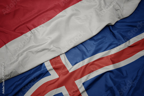 waving colorful flag of iceland and national flag of indonesia.