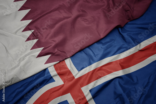 waving colorful flag of iceland and national flag of qatar.