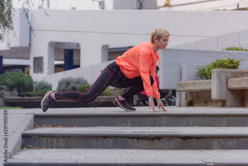 Young female runner prepairing for jogging in the city street. Fit body requires hard work. Urban sport concept. Young female exercising in sport clothes.