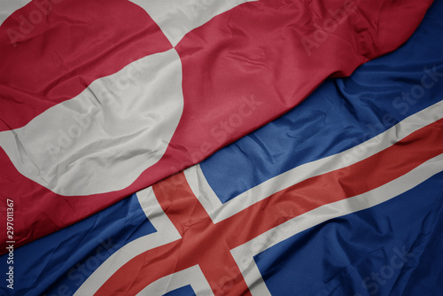 waving colorful flag of iceland and national flag of greenland.