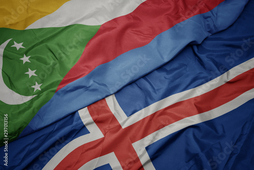 waving colorful flag of iceland and national flag of comoros.