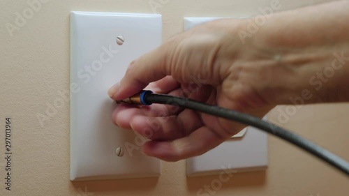 Male electrician disconnecting coax cable cord from wall outlet. Coaxial wire connection for TV and high speed broadband internet. Canceling television service.