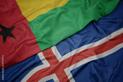 waving colorful flag of iceland and national flag of guinea bissau.