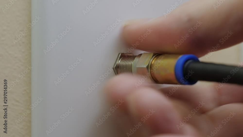 Male electrician disconnecting coax cable cord from wall outlet