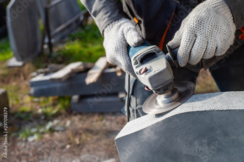 Man's hands holding angle grinder and grinding a stone