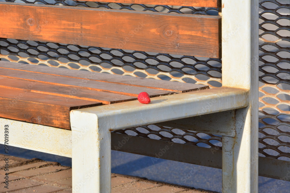 Red strawberry lies alone on a bench in the summer in the city Red strawberry lies alone on a bench in the summer in the city