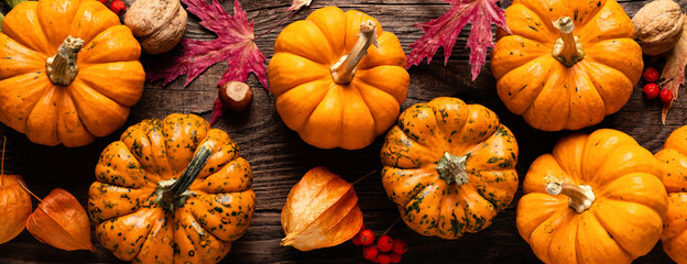 Autumn decorative pumpkins with fall leaves on wooden background. Thanksgiving or halloween holiday, harvest concept. Top view, copy space. Greeting card