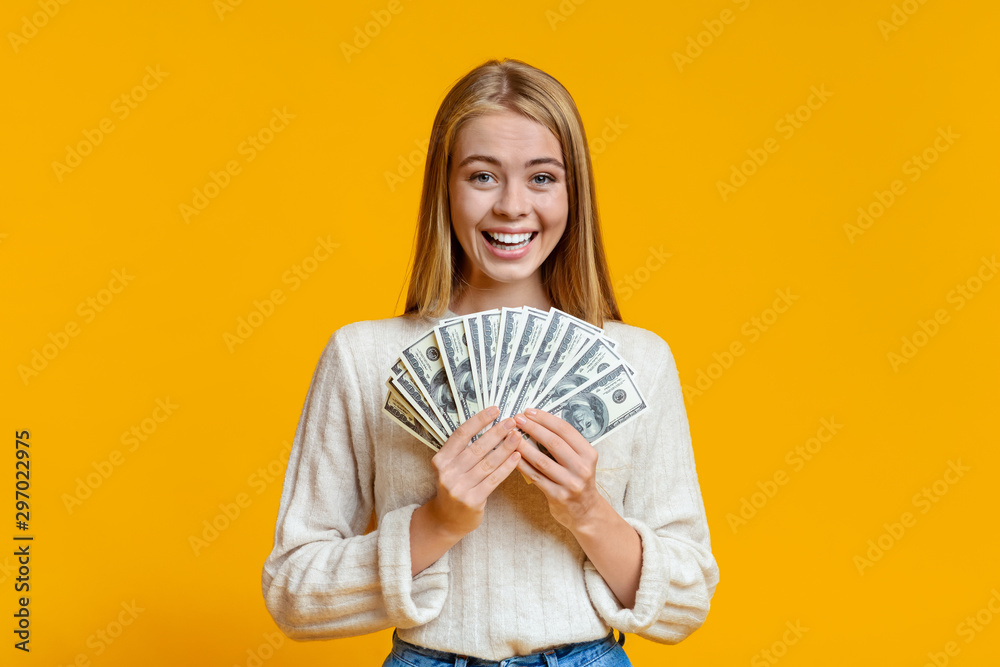 Joyful young girl holding fan of dollars in hands Joyful young girl holding fan of dollars in hands