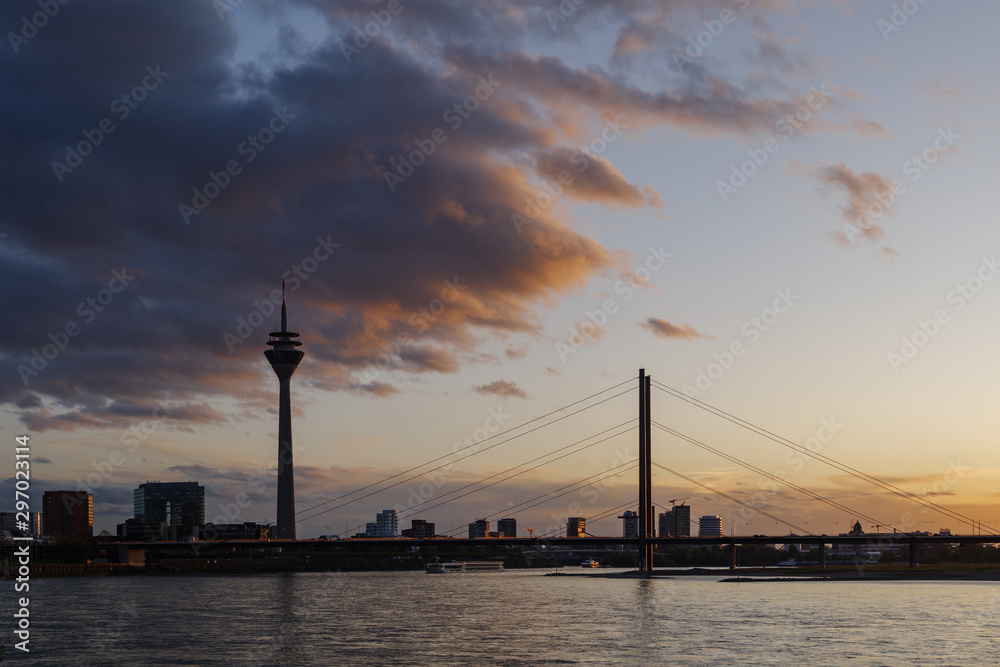 Outdoor silhouette scenery of Düsseldorf City skyline, downtown, tower bridge, riverside and Rhine River, and beautiful background of dramatic twilight sunset sky. 