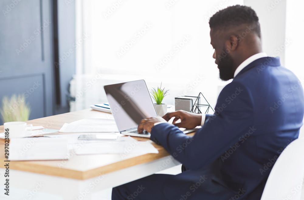 Back view of young businessman working with laptop in office Back view of young businessman working with laptop in office