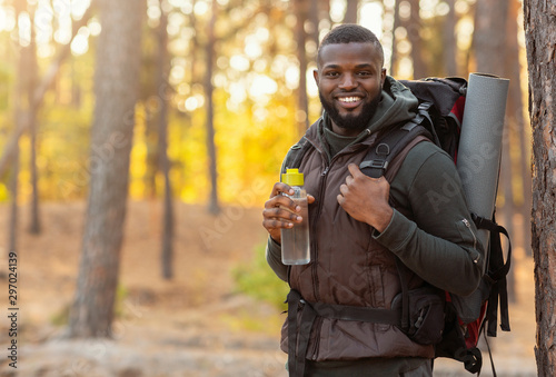 African man wearing backpack standing over forest background