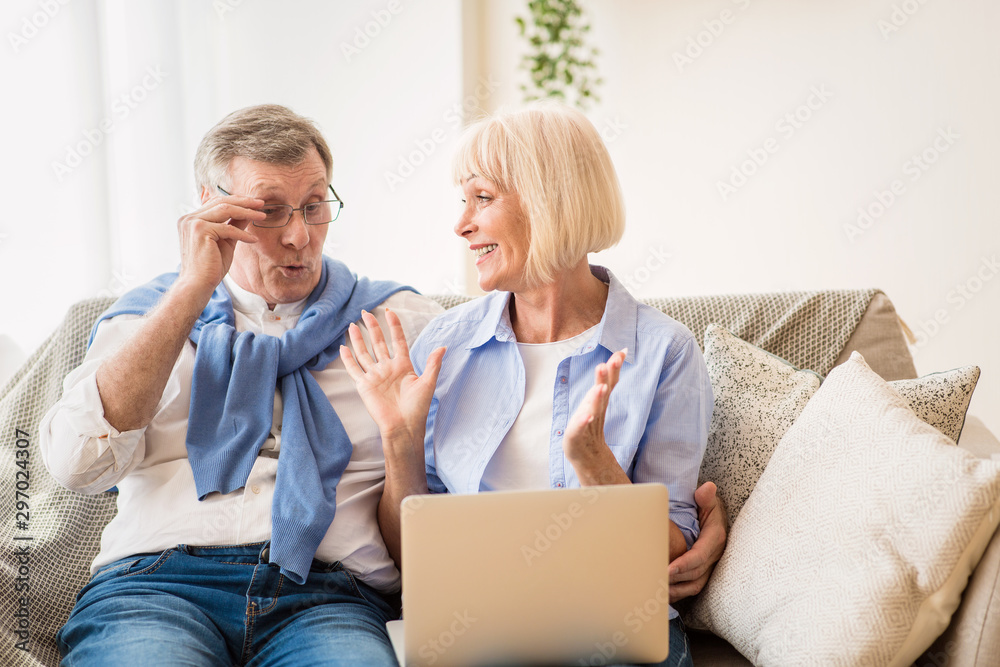 Emotional senior couple reading good news on laptop