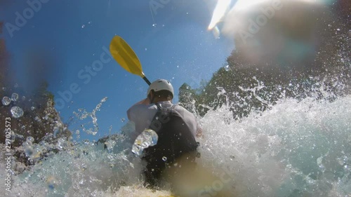 A man kayaking through rapids, filmed in slow motion photo