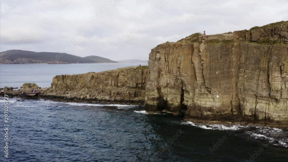 Aerial view of amazing high coastline, flying seagulls and zingara woman dancing on cliff summit. Blue ocean. Aerial view of amazing high coastline, flying seagulls and zingara woman dancing on cliff summit. Blue ocean.