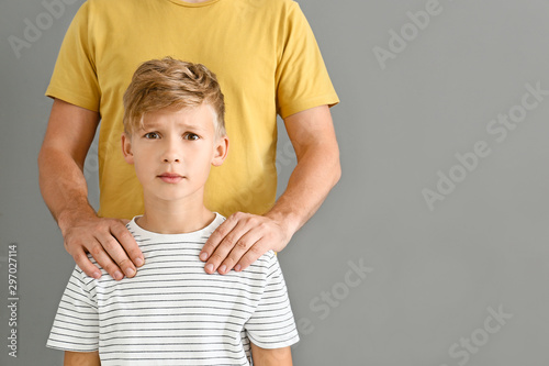 Принти на полотні Father putting hands on shoulders of his scared son against grey background