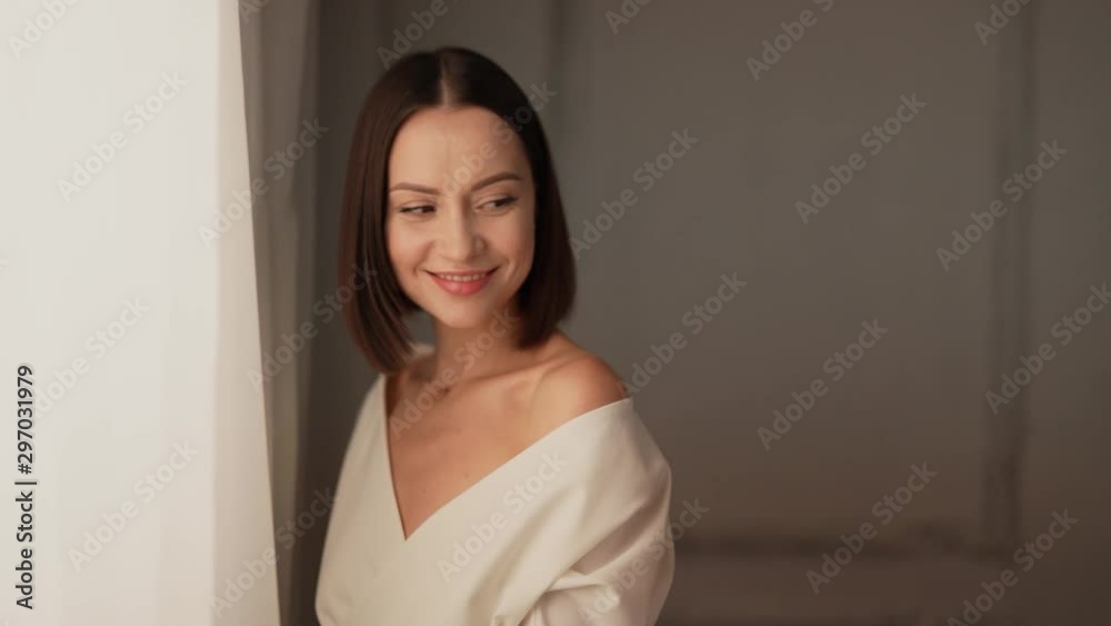 Closeup portrait of smiling woman looking at camera in studio. Young attractive confident brunette lady smiling on white background. Female natural beauty. Slow motion video Closeup portrait of smiling woman looking at camera in studio. Young attractive confident brunette lady smiling on white background. Female natural beauty. Slow motion video
