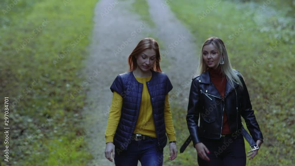 Two attractive girls having chat and walk outdoors spotting something Two attractive girls having chat and walk outdoors spotting something