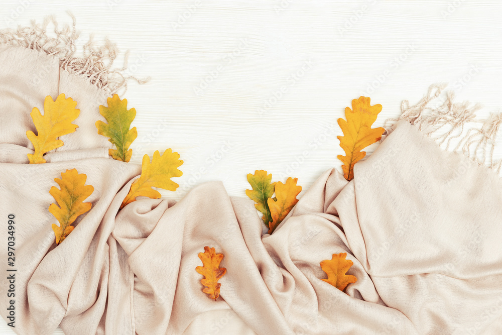 Obraz premium Bright yellow autumn leaves flat lay on white wooden background with copy space. Many leaves of oak tree and cozy warm palantine, autumnal theme. Top view.