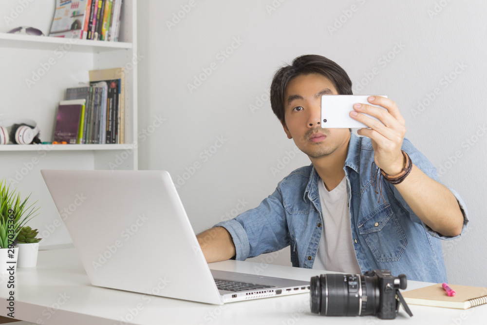 Asian Photographer or Freelancer Selfie or Take Photo by Smartphone in Home Office Asian Photographer or Freelancer Selfie or Take Photo by Smartphone in Home Office