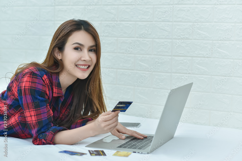 Young woman holding credit card and using laptop computer. Online shopping concept Young woman holding credit card and using laptop computer. Online shopping concept