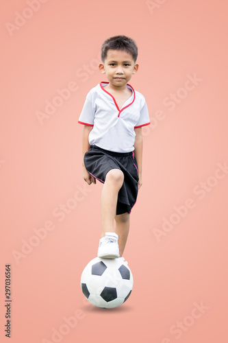 The boy in sportswear wearing sneakers is stepping on a soccer ball isolated on pastel color background, with clipping path. © ETAP
