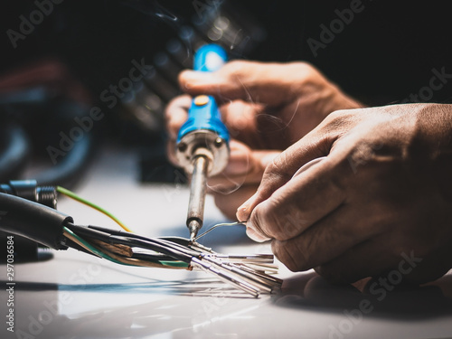 Electricians are using a soldering iron to connect the wires to the metal pin with soldering lead. photo