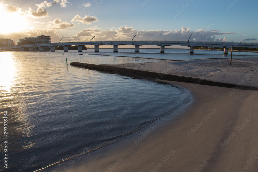 Landscape View Large Bridge Over Calm Blue Water At Sunrise With Orange Sky