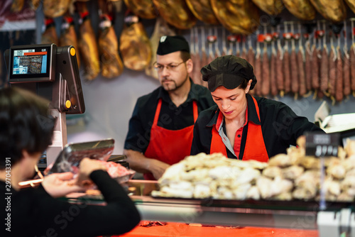 Butchers attending a customer in a butcher s shop