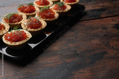 Red caviar in tartalets on a wooden table