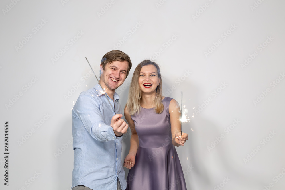 Party, new year, christmas, and holidays concept - young couple holding sparklers on white background Party, new year, christmas, and holidays concept - young couple holding sparklers on white background
